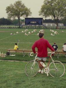 Bicyclist watches lacrosse practice.